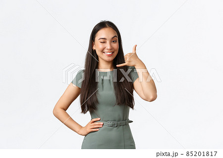 Small business owners, startup and work from home concept. Smiling cheeky asian woman winking and smiling, encourage clients give her call, shop assistant answering client questiones via phone 85201817