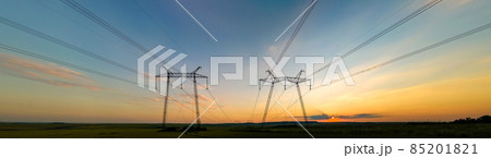 Dark silhouette of high voltage towers with electric power lines at sunrise. 85201821