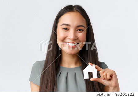 Insurance, loan, real estate and family concept. Close-up of happy smiling asian woman showing small paper house miniature in hands and looking at camera, found perfect apartment, white background Insurance, loan, real estate and family concept. Close-up of happy smiling asian woman showing small paper house miniature in hands and looking at camera, found perfect apartment, white background 85201822