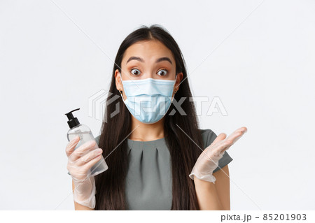 Small business owners, covid-19, preventing virus measures concept. Excited asian woman in medical mask and gloves react to surprising news while holding hand sanitizer, white background Small business owners, covid-19, preventing virus measures concept. Excited asian woman in medical mask and gloves react to surprising news while holding hand sanitizer, white background 85201903