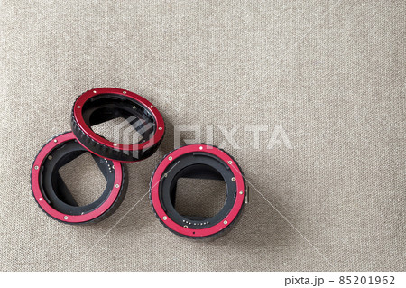 Close-up of macro rings, camera adapters on light cloth copy space background. Modern technology and photography equipment concept. Close-up of macro rings, camera adapters on light cloth copy space background. Modern technology and photography equipment concept. 85201962