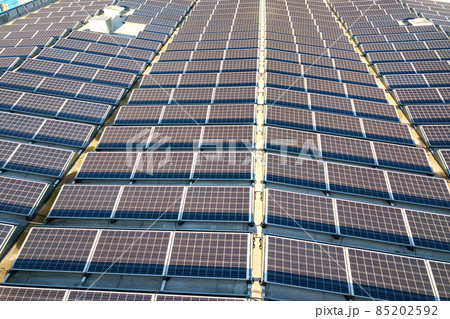 Aerial view of many photo voltaic solar panels mounted of industrial building roof. Aerial view of many photo voltaic solar panels mounted of industrial building roof. 85202592