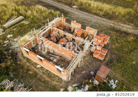 Aerial view of building site for future brick house, concrete foundation floor and stacks of yellow clay bricks for construction. Aerial view of building site for future brick house, concrete foundation floor and stacks of yellow clay bricks for construction. 85202619