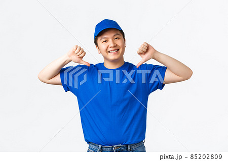 Friendly-looking smiling and confident asian delivery guy in blue uniform pointing at himself. Courier promote his company service, guarantee fast and safe shipping, standing white background Friendly-looking smiling and confident asian delivery guy in blue uniform pointing at himself. Courier promote his company service, guarantee fast and safe shipping, standing white background 85202809