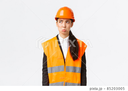 Gloomy and offended young asian female construction manager, industrial woman in safety helmet complaining or whining, pouting sad and looking upper left corner disappointed Gloomy and offended young asian female construction manager, industrial woman in safety helmet complaining or whining, pouting sad and looking upper left corner disappointed 85203005