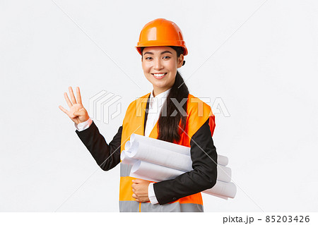 Smiling confident asian female engineer, construction manager in safety helmet, carry blueprints, showing four fingers, ensure building finished in time, standing white background upbeat 85203426