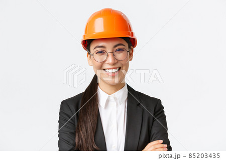 Smiling leader of the team, asian female chief engineer in safety helmet and suit cross arms confident, smiling happy at camera, introduce enterprise, standing white background Smiling leader of the team, asian female chief engineer in safety helmet and suit cross arms confident, smiling happy at camera, introduce enterprise, standing white background 85203435