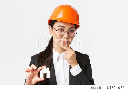 Thoughtful creative female asian architect in helmet and business suit creating new ideas of design, showing home maket and thinking, making cunning face, pondering plan of construction Thoughtful creative female asian architect in helmet and business suit creating new ideas of design, showing home maket and thinking, making cunning face, pondering plan of construction 85204072