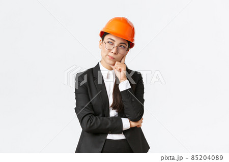 Thoughtful creative female asian chief architect, construction engineer thinking, wearing safety helmet and suit, pondering best choice for building, standing white background Thoughtful creative female asian chief architect, construction engineer thinking, wearing safety helmet and suit, pondering best choice for building, standing white background 85204089