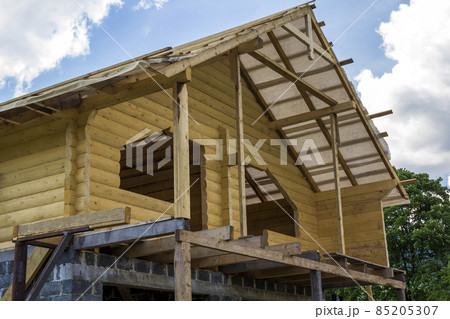 New cottage of natural lumber materials under construction. Wooden walls and roof on high brick stone garage. Property, investment, professional building and reconstruction concept. New cottage of natural lumber materials under construction. Wooden walls and roof on high brick stone garage. Property, investment, professional building and reconstruction concept. 85205307