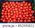 Red tomatoes for sale at vegetable market, close up. Boxes full of tomatoes in shop. Fresh tomato at the greengrocer's stall. Ripe tomatoes on table. Vegetable. 85205821