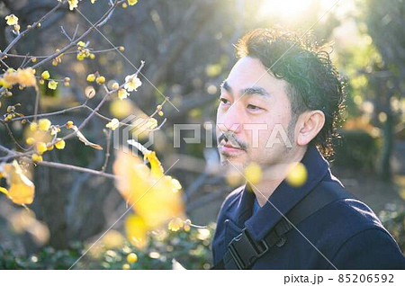蝋梅の花に囲まれて香りを楽しむ男性 85206592