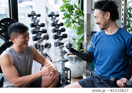 筋トレを教えるトレーナーとプライベートレッスンをダンベルを教わる人	 85210627