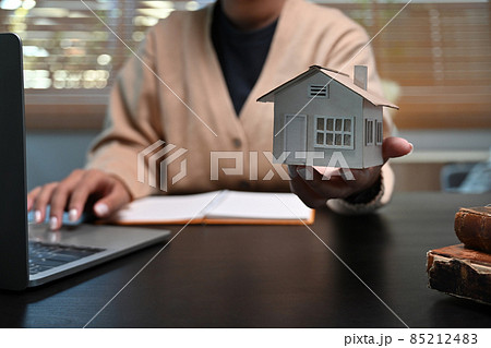 Woman using laptop computer and showing house model. Mortgage and real estate investment concept. Woman using laptop computer and showing house model. Mortgage and real estate investment concept. 85212483