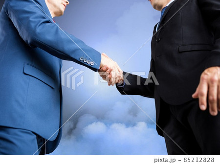 Mid section of two businessmen shaking hands against clouds in the sky 85212828