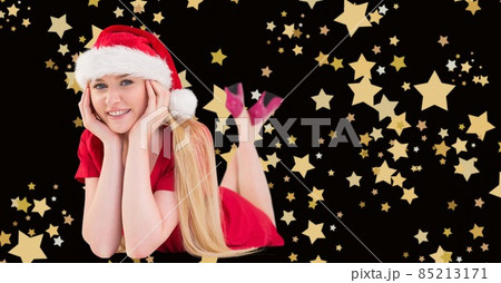 Composite image of caucasian woman wearing a santa hat against golden star icons on black background Composite image of caucasian woman wearing a santa hat against golden star icons on black background 85213171
