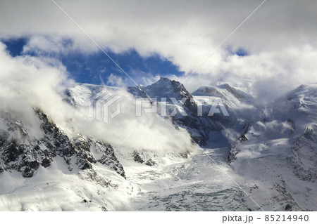 Breathtaking aerial view of Mont Blanc mountain peak covered with shiny snow, ice and glaciers under blue sky with puffy white clouds on the French side of Alps on a clear cold sunny winter day 85214940