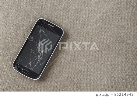Black old cellphone with cracked screen on light cloth copy space background. Gadget repair and maintenance concept. 85214945