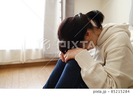 部屋で床に座り込み顔を伏せる女性 部屋で床に座り込み顔を伏せる女性 85215284