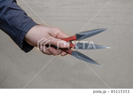 A hand with three knives. Adult male holding throwing knives. A hand with three knives. Adult male holding throwing knives. 85215353