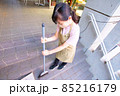 マンションの共用部を箒で掃くエプロン姿の女性 85216179