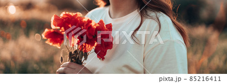 Woman hand holding red poppies bouquet at sunset in the field 85216411