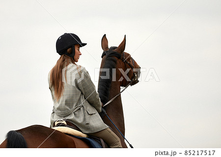 Beautiful young woman riding a horse on the field. Sideways to the camera. Freedom, joy, movement Beautiful young woman riding a horse on the field. Sideways to the camera. Freedom, joy, movement 85217517