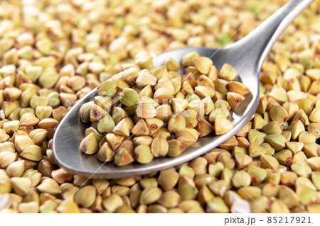 Raw green buckwheat in spoon. Uncooked grains. Macro Raw green buckwheat in spoon. Uncooked grains. Macro 85217921