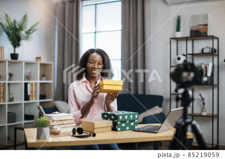 African woman recording video while unpacking gift boxes 85219059