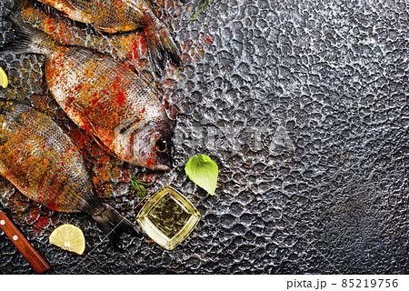 Raw fish with herbs, lemon and olive oil on dark textured background. Raw fish with herbs, lemon and olive oil on dark textured background. 85219756