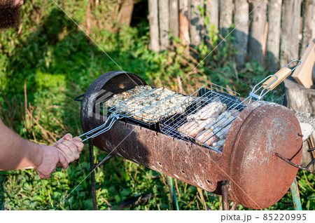 cooking raw meat in a grid on the barbeque grill 85220995