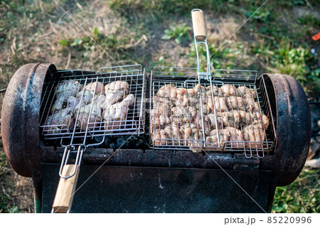 cooking raw meat in a grid on the barbeque grill 85220996