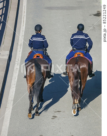 Two riders in uniform with the inscription GENDARMERIE on the back move around the city on horseback. Two riders in uniform with the inscription GENDARMERIE on the back move around the city on horseback. 85221249