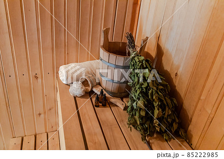 Traditional old Russian bathhouse SPA Concept. Interior details Finnish sauna steam room with traditional sauna accessories set basin birch broom towel aroma oil. Relax country village bath concept Traditional old Russian bathhouse SPA Concept. Interior details Finnish sauna steam room with traditional sauna accessories set basin birch broom towel aroma oil. Relax country village bath concept 85222985