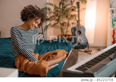 Joyful woman sitting near synthesizer at home Joyful woman sitting near synthesizer at home 85223759
