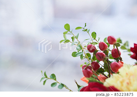 Part of the bouquet with the edge of barberry berries, green leaves, red rose. The concept of the holiday. Copy space. High quality photo 85223875