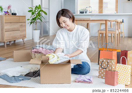 リビングで着れなくなった子供服を段ボールに詰める主婦 85224466