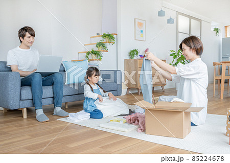 ママと衣類の片付けのお手伝いをする小学生の女の子とソファに座ってパソコン作業をするパパ ママと衣類の片付けのお手伝いをする小学生の女の子とソファに座ってパソコン作業をするパパ 85224678