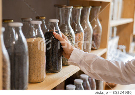 Woman in a store selling cereals by weight in an eco store. Trade concept without plastic packaging 85224980