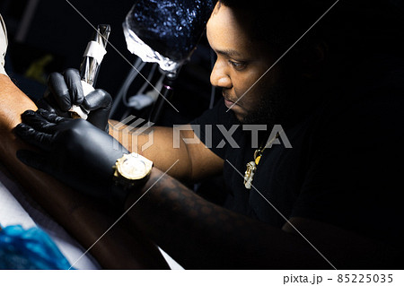 The portrait of the tattoo artist concentrated on his work. Closeup. The portrait of the tattoo artist concentrated on his work. Closeup. 85225035
