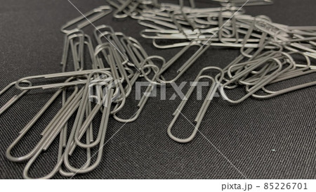 Lots of metal paper clips scattered across the black table 85226701