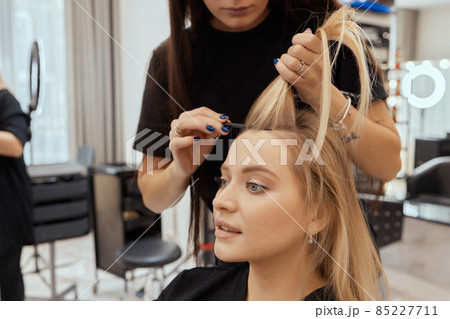 Hair stylist makes bouffant using comb on thin strands. Shatush technique for hair lightening. 85227711