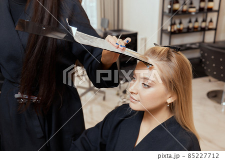 Hair stylist makes bouffant using comb on thin strands. Shatush technique for hair lightening. 85227712