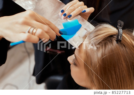 Hair stylist makes bouffant using comb on thin strands. Shatush technique for hair lightening. 85227713