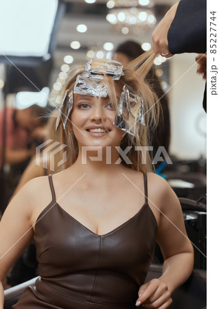 Hair stylist makes bouffant using comb on thin strands. Shatush technique for hair lightening. 85227744