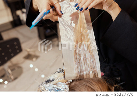 Hair stylist makes bouffant using comb on thin strands. Shatush technique for hair lightening. 85227770
