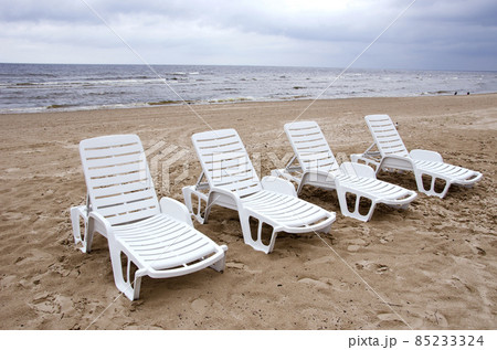 empty white chairs near sea on beach sand 85233324