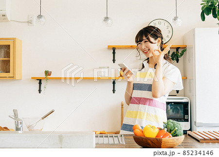 キッチンでスマホを持つ女性（スマホ・笑顔） 85234146