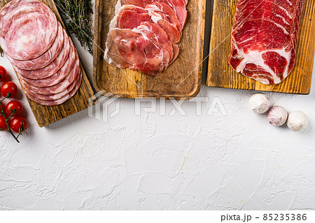 Cold smoked meat slices prosciutto, on white stone table background, top view flat lay, with copy space for text 85235386