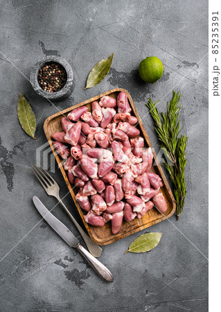 Raw uncooked chicken gizzards, chicken hearts, on gray stone table background, top view flat lay Raw uncooked chicken gizzards, chicken hearts, on gray stone table background, top view flat lay 85235391